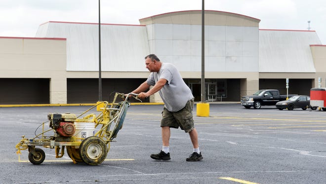 David Bailey of Bailey's Asphalt Services paints lines the parking lot of the former Super K Mart in South Zanesville. Rural King will open in the building in August.