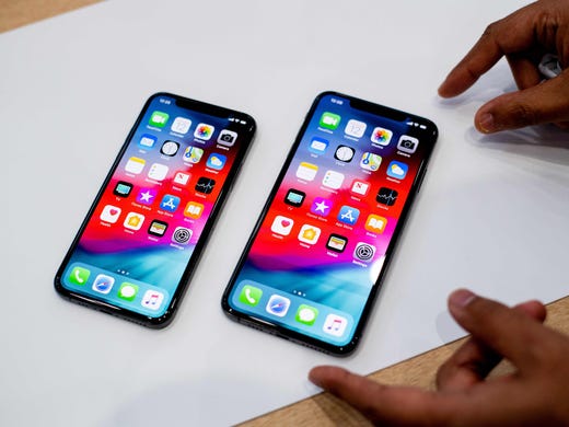 An Apple iPhone Xs Max, right, and an iPhone Xs rest