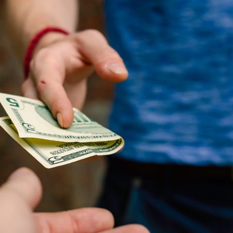 Person handing over a $5 bill