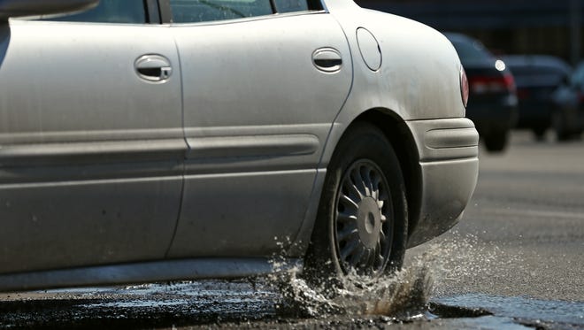 A car splashes through a pothole on National Avenue near Brower Street.