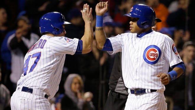 Chicago Cubs' Miguel Montero, left, celebrates with Addison Russell after they scored on a single hit by Dexter Fowler during the eighth inning of a baseball game against the Cincinnati Reds Thursday, April 14, 2016, in Chicago. (AP Photo/Nam Y. Huh)