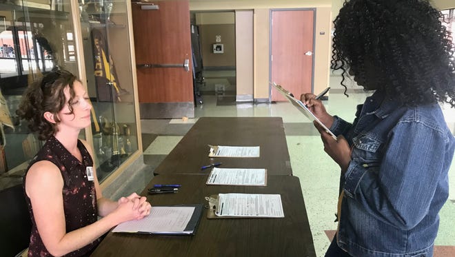 Bethany Phillips, left, assists 18-year-old Dorcas Nzoamba with registering to vote at Abilene High School Friday.