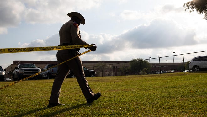 A Texas Department of Public Safety officer places crime scene tape across Santa Fe High School on May 19, 2018, the day after a mass shooting.