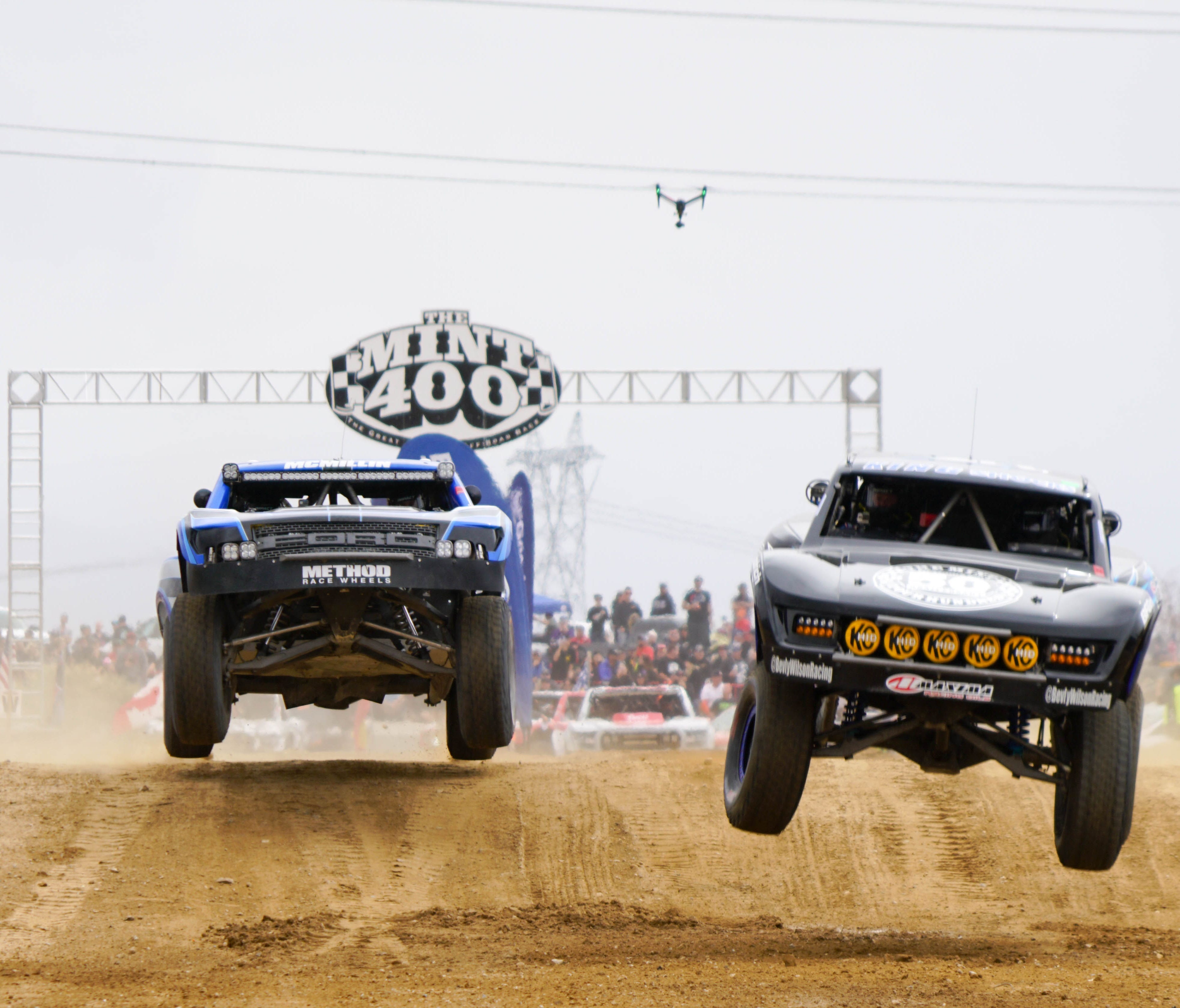 Trucks launch off one of the first jumps at the Mint 400, watched over by a drone.      