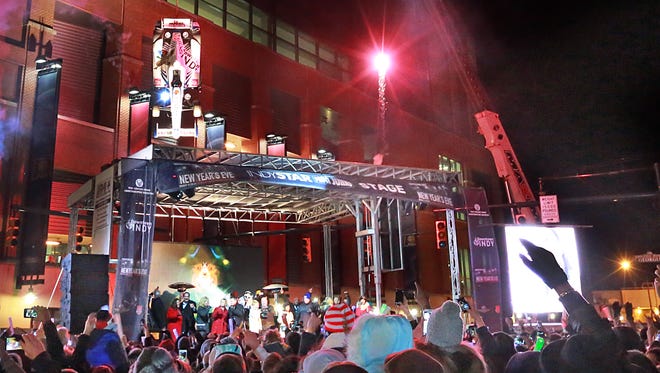 The glow of fireworks paints the scene during the stroke of midnight at the Downtown Indy New Year's Eve celebration where an IndyCar was lowered over the main stage at Georgia and Pennsylvania Streets.