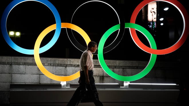 A man walks past the Olympic rings Tuesday, July 23, 2019, in Tokyo, as Japan marks a year-to-go until hosting the summer games with Olympic medals being unveiled Wednesday as part of daylong ceremonies around the Japanese capital.  The Summer Olympics will return to Tokyo next year for the first time since 1964.  (AP Photo/Jae C. Hong)