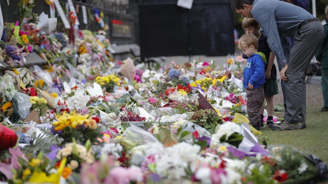 Mourners lay flowers on a wall at the Botanical Gardens in Christchurch, New Zealand, Monday, March 18, 2019. A steady stream of mourners paid tribute at makeshift memorial to the 50 people slain by a gunman at two mosques in Christchurch, while dozens of Muslims stood by to bury the dead when authorities finally release the victims' bodies. (AP Photo/Vincent Thian)