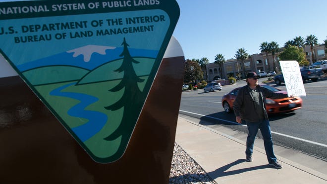 Ernie Jessop, a resident of Motoqua who is concerned about the Bureau of Land Management's land use plans for the area around his home, holds a sign to protest the plan outside the St. George offices of the BLM Thursday, Nov. 12, 2015.