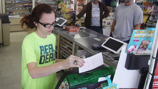 Taylor Winnie, sales clerk at the Quick Food Mart in Fort Myers, scans Powerball lottery tickest for customers during her shift on Thursday. The jackpot has reached $800 million.