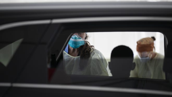 A child is silhouetted before Brockton Neighborhood Health Center nurse practitioner Kelly Nagi tests him and his brother at the drive-thru coronavirus testing site at Brockton High School on Wednesday, July, 29, 2020.
