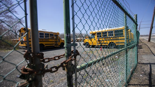 In an April 19, 2020, file photo, Brockton Public School buses sit unused in a lot on Oak Street after schools were closed due to the coronavirus pandemic.