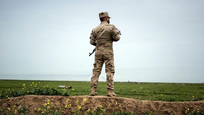 In this April 9, 2016, photo, a soldier who is part of the Shammar tribal militia stands guard on the border with Syria, in Rabia, northwestern Iraq.