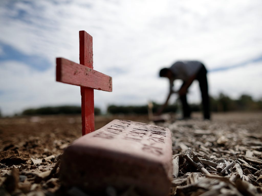 Jesus Salvador places crosses in a pauper's cemetery where hundreds of unidentified migrants are buried in Holtville, Calif. As part of a Valentine's Day celebration, a group from San Diego and the Imperial Valley replaced wooden crosses on the grave