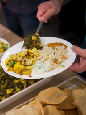 Guests fill their plates with vegetarian dishes made by Chef Jes Thomas during her Taste of India cooking demonstration at the Central Collective in Knoxville on Sunday, Dec. 11, 2016. 