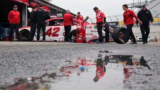 Under threatening skies, crew members work on the race car of Kyle Larson (42) in the garage area as teams prepare for practice for Sunday's  NASCAR Sprint Cup series auto race Saturday at Dover International Speedway.
