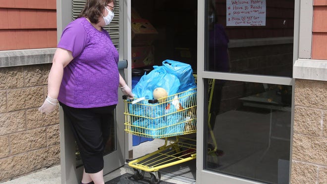 Brenda Stottsberry, a case worker with the Salvation Army, takes a shopping cart of food from their pantry in Massillon on June 10. Those in need make an appointment and the goods are taken to their vehicles. The Salvation Army has seen an increase in the number of people seeking help during the COVID-19 pandemic.