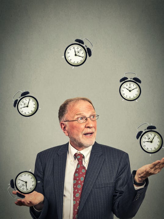 business man in suit juggling multiple alarm clocks