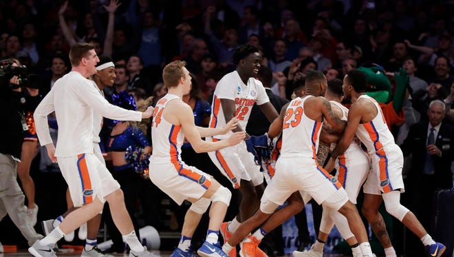 Florida players celebrate after a last-second shot by guard Chris Chiozza (11) to beat Wisconsin in overtime of an East Regional semifinal of the NCAA men's college basketball tournament, early Saturday, March 25, 2017, in New York. Florida won 84-83. (AP Photo/Julio Cortez)