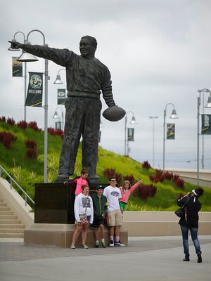 People take pictures and linger near the Curly Lambeau statue at Lambeau Field in Green Bay.