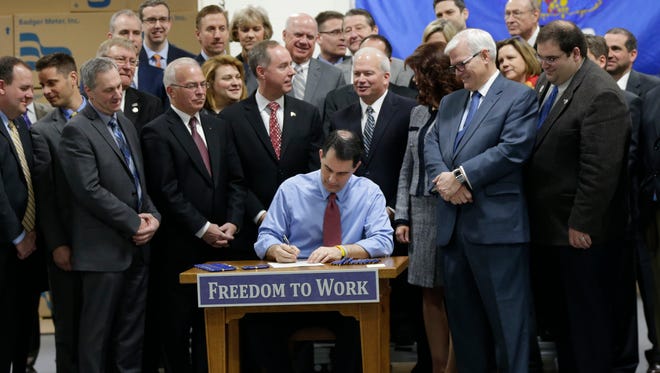 Wisconsin Gov. Scott Walker signs a right-to-work bill into law Monday at Badger Meter in Brown Deer.  The new law, which takes effect immediately, makes Wisconsin the 25th right-to-work state and the first to do it since Michigan and Indiana in 2012.