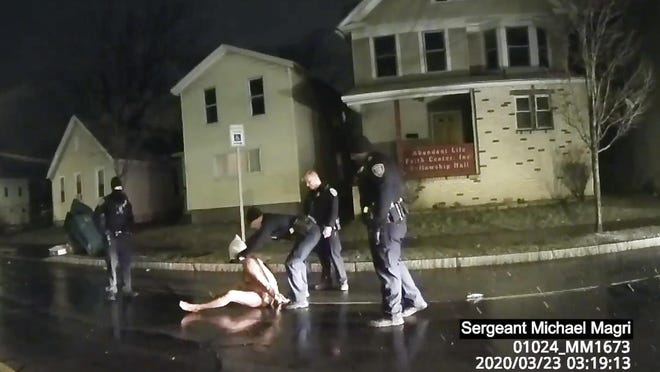 In this image taken from police body camera video provided by Roth and Roth LLP, a Rochester police officer puts a hood over the head of Daniel Prude, on March 23, 2020, in Rochester, N.Y. Video of Prude, a Black man who had run naked through the streets of the western New York city, died of asphyxiation after a group of police officers put a hood over his head, then pressed his face into the pavement for two minutes, according to video and records released Wednesday, Sept. 2, 2020, by his family. Prude died March 30 after he was taken off life support, seven days after the encounter with police in Rochester.