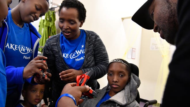 Adrien Nkurunziza (right) shows a jewelry gift from J.C. Penney's to his 16 year-old niece Mutoni Jolie Saturday at the store. Mutoni, 16, was on a shopping spree at the Mall of Abilene with her mother Clementine Nyiramanyaa (center), sister Bella Mbabazi, 14, 4 year-old brother Joshua Mugisha, and her other two siblings thanks to the Make-A-Wish Foundation.