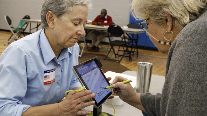 Voter Janice Christian, right, signs in with poll worker Valerie Fronczak in the Woodward Park Community Center on Election Day in 2017. Ohio's county boards of elections still need to recruit nearly 12,000 Democrats and almost 15,000 Republicans to be poll workers to hit the state's goal of being prepared for cancellations.
