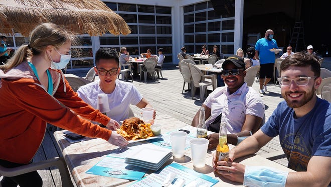 Friends Phuck Nguyen, left, Sebastian Jeanfrancios, center, and Blake Calman, right, enjoy a round of beer and nachos at Bernie's Beach Bar at Hampton Beach earlier this summer.