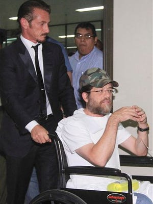 In this 2012 file photo, actor Sean Penn pushes U.S. businessman Jacob Ostreicher in a wheelchair, during a recess at Ostreicher's hearing in Santa Cruz, Bolivia. In the year since Ostreicher was spirited out of Bolivia, the 55-year-old has struggled to rebuild a life upended by corrupt officials who tried to extort him and imprisoned him without charge. Ostreicher's ordeal began with an attempt to salvage ill-fated investment in Bolivian rice farms, devolved into a Third World prison nightmare and climaxed with an escape engineered by actor Sean Penn.