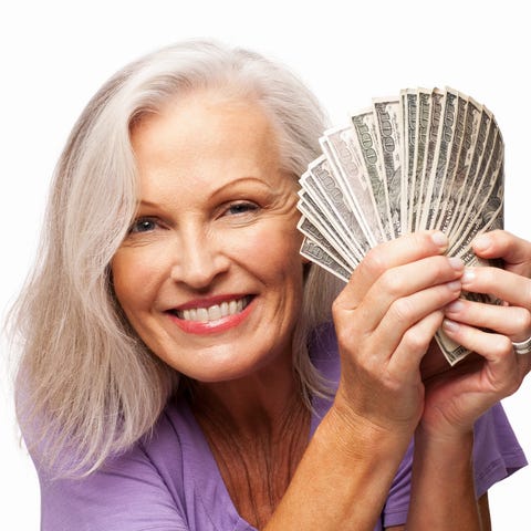 Smiling older woman holding fan of hundred dollar 