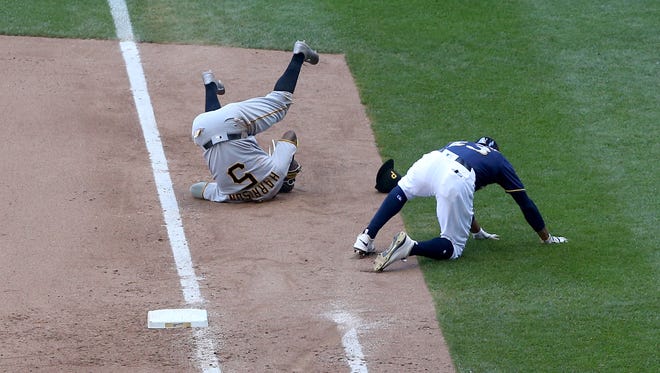 Pittsburgh's Josh Harrison and Milwaukee's Keon Broxton fall to the ground after colliding at first base in the sixth inning.