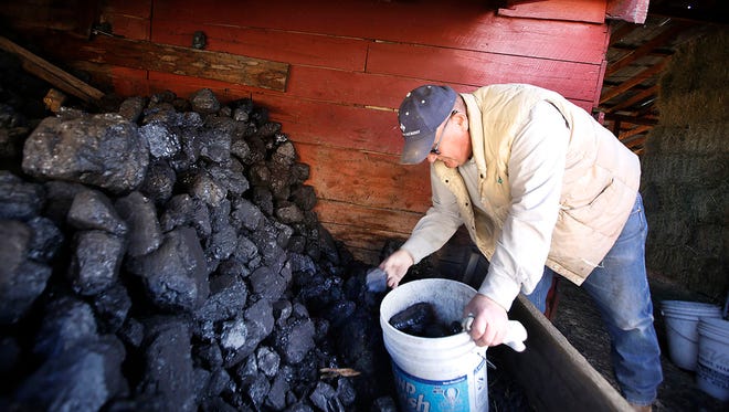 In this Friday, Feb. 2, 2018, photograph, Monte Miller loads up a bucket of coal at his home in Bayfield, Colo. Miller purchases coal from Hay Gulch Coal in La Plata County. Coal provides an economical source of heat through the winter but the fossil fuel is tied to health and environmental hazards. (Jerry McBride/Durango Herald via AP)