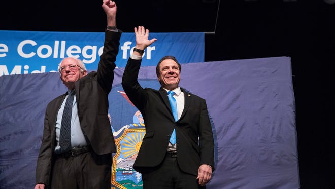 New York Gov. Andrew Cuomo, right and Vermont Sen. Bernie Sanders wave at the audience as they arrive onstage at an event at LaGuardia Community College, Tuesday, Jan. 3, 2017, in New York.  (AP Photo/Mary Altaffer)