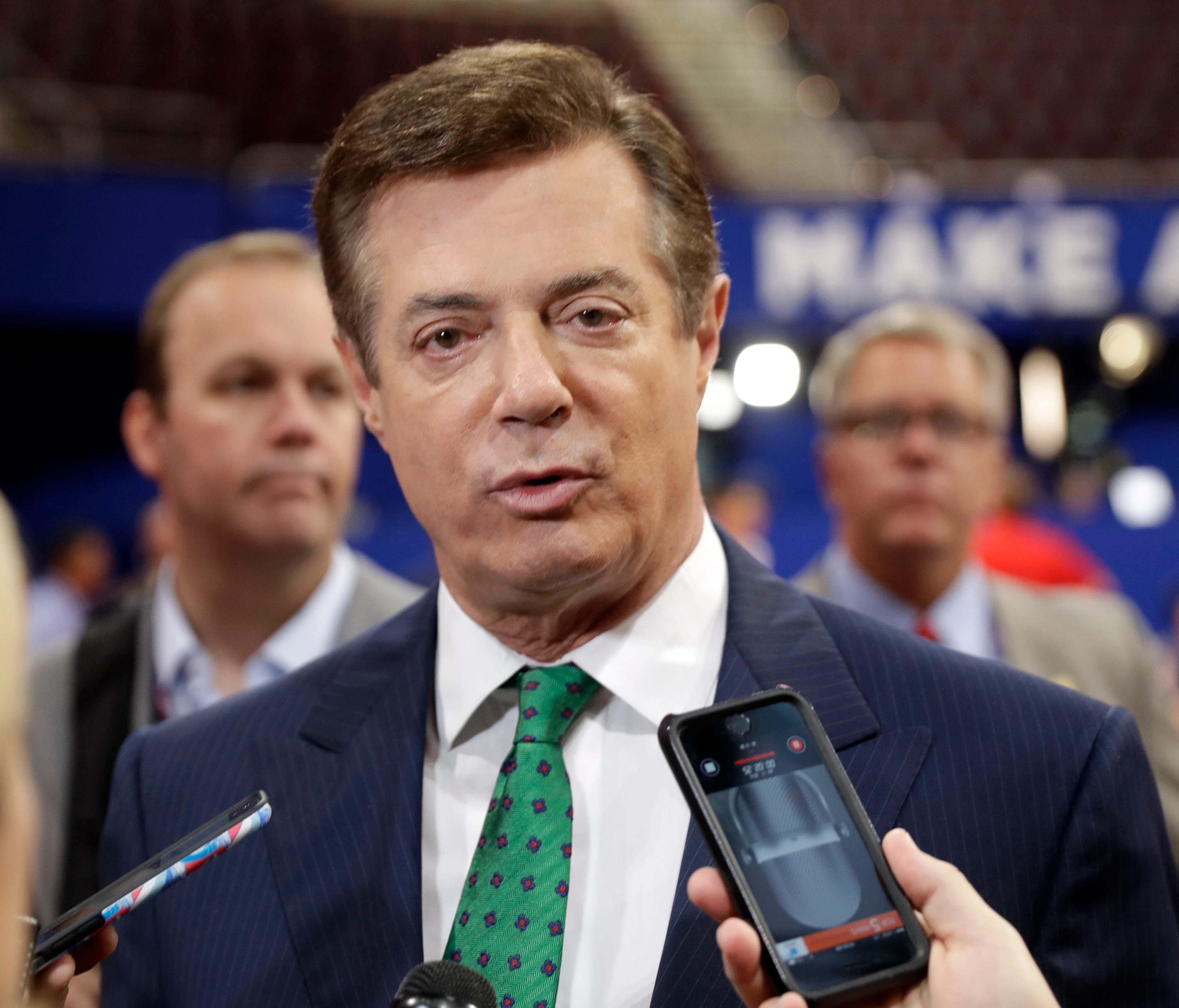 In this July 17, 2016 file photo, Trump campaign chairman Paul Manafort talks to reporters on the floor of the Republican National Convention at Quicken Loans Arena in Cleveland as Rick Gates listens at back left. President Donald Trump's administrat