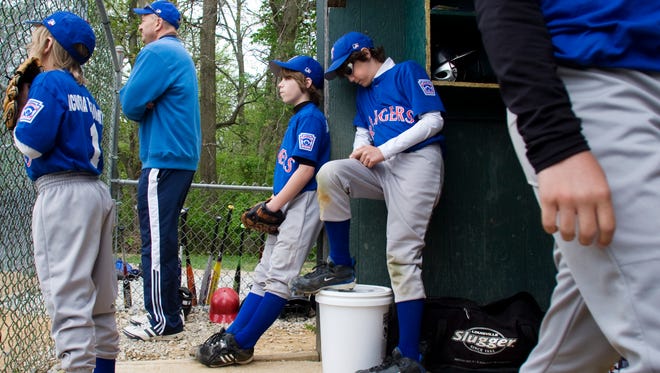 Rangers players wait with a coach in the dugout during a game at Eagle Park on the first day of 2010 South Hanover Little League.