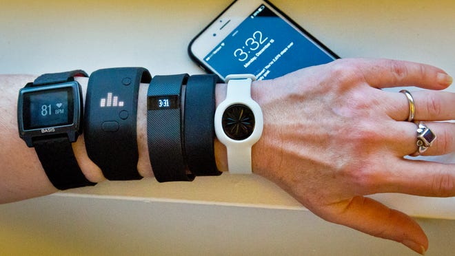 Fitness trackers, from left, Basis Peak, Adidas Fit Smart, Fitbit Charge, Sony SmartBand, and Jawbone Move, next to an iPhone. The best device for you will depend on your current fitness levels and needs.