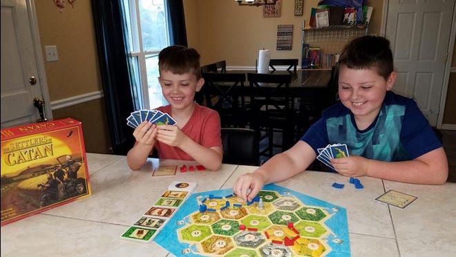 James and Braeden Will play the board game "Settlers of Catan" at their home.