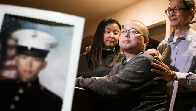 U.S. Marine veteran of Iraq and Africa Michael Chiang, 33, of Troy sits at the table of his home with his sister Theresa Chiang, 32, formerly of Clinton Township, and father Taihsiang Chiang, 64, on Tuesday Jan. 5, 2016.