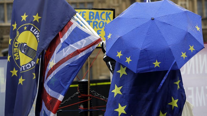 An anti-Brexit demonstrator shelters under an umbrella in the pattern of the European Union flag outside parliament in London, Jan. 24, 2019.