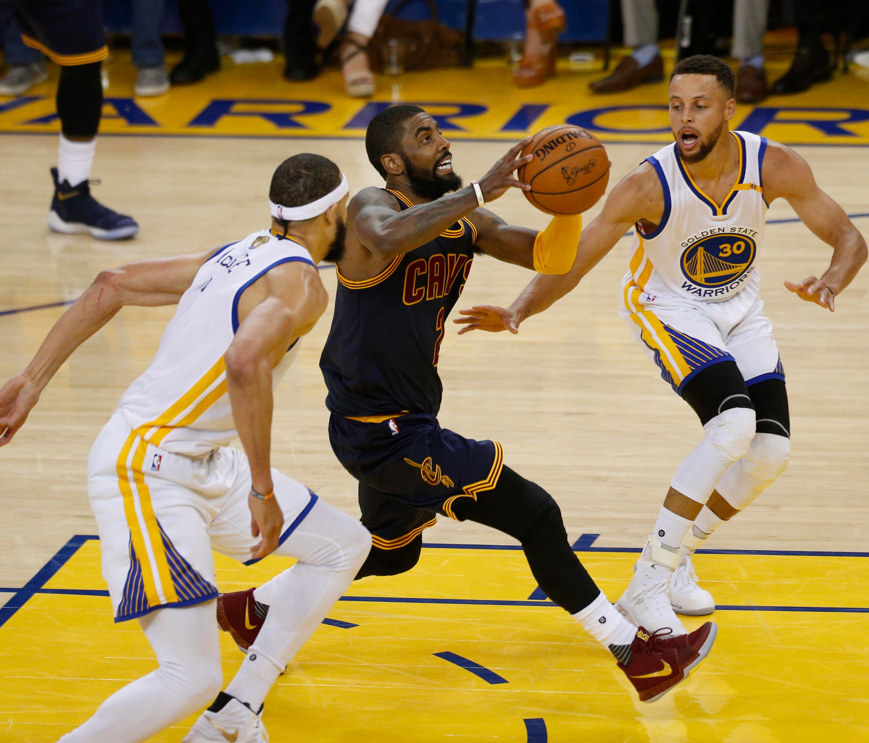 Cleveland Cavaliers guard Kyrie Irving (2) drives to the basket against Golden State Warriors guard Stephen Curry (30) and center JaVale McGee (1) in the first half of the NBA Finals at Oracle Arena.
