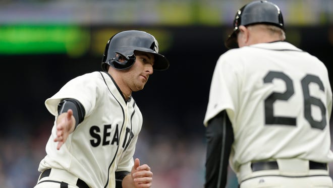 Seattle Mariners' Brad Miller, left, is greeted by third base coach Rich Donnelly after hitting a solo home run on a pitch from Boston Red Sox's Rick Porcello during the first inning of a baseball game on Saturday, May 16, 2015, in Seattle. Both teams are wearing uniforms of Negro League teams of 1946, Seattle is the Seattle Steelheads and Boston that of the Boston Giants.