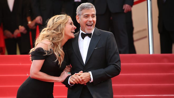 Julia Roberts tells George Clooney a little secret on the Cannes red carpet Thursday night.