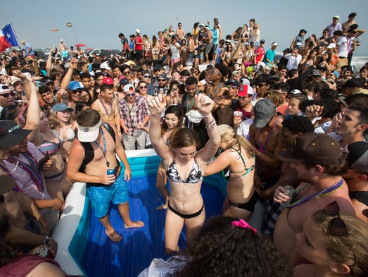 A crowd gathers around an inflatable pool on the beach