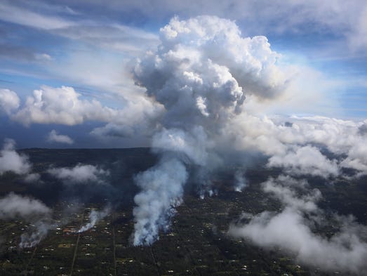 A plume of volcanic gas mixed with smoke from fires