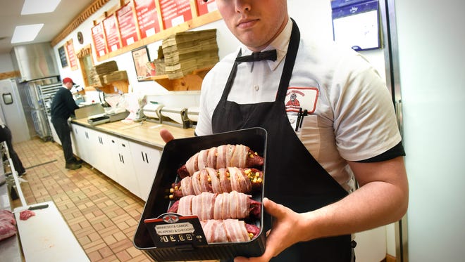 Austin Rasmussen holds a tray of bacon-wrapped, Jalapeno and Cheddar "Minnesota Canoes"  Tuesday, May 8, at Von Hanson's Meat Market in Waite Park. 