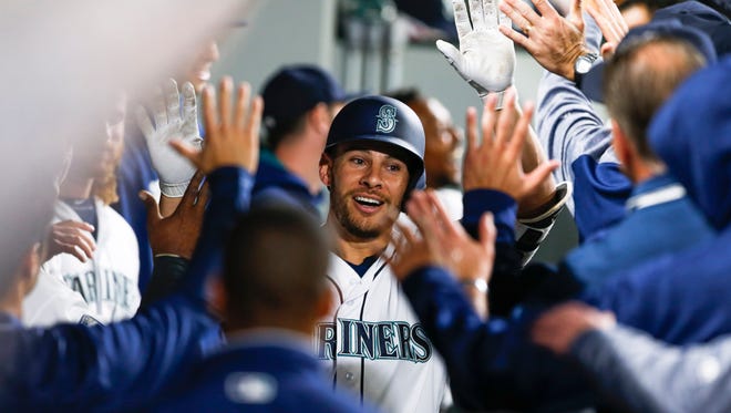 Seattle Mariners first baseman Danny Valencia  is greeted in the dugout after hitting a solo-home run against the Los Angeles Angels during the seventh inning at Safeco Field.