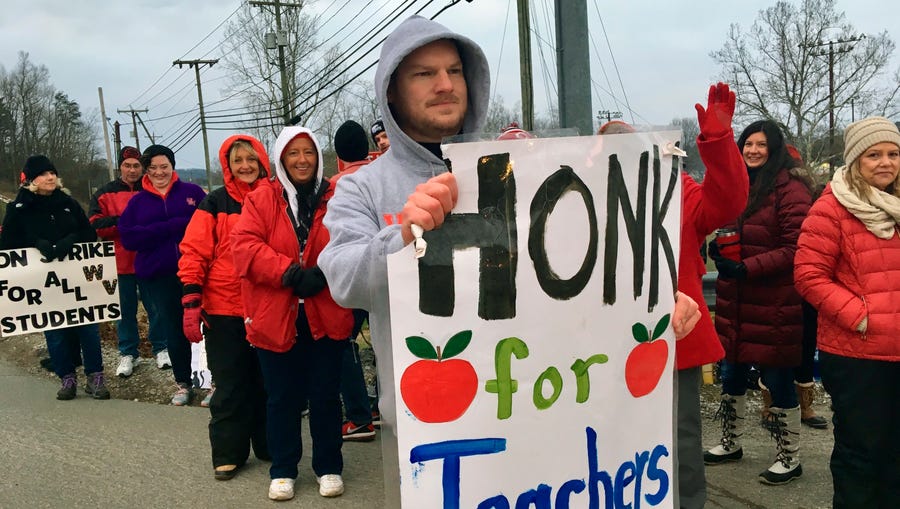 Striking teachers wave at passing cars outside Poca