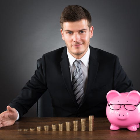 Smiling man sitting in front of piggy bank with co