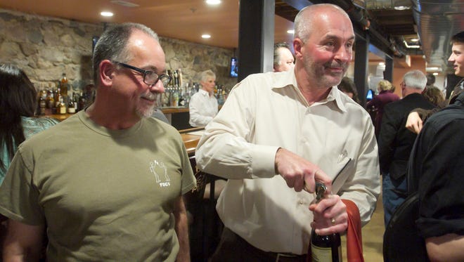 Joe Parker, right, opens a bottle of Sawbuck California Cabernet with his 2FOG’s Pub partner Brian Atkinson at his side in a friends and family pre-opening party at the downtown Howell bar.