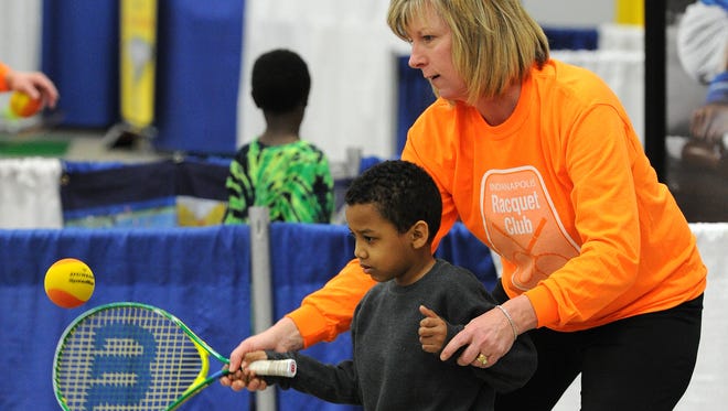Melissa Havel, the Indianapolis Racquet Club teaching pro, instructs Jeremy Lucas, 7, during the Indianapolis Sport & Fitness Show,Jan. 3, 2014, inside the Champions Pavilion at the Indiana State Fairgrounds.